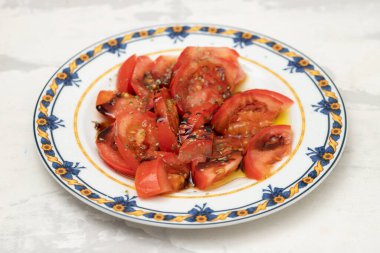 salad with fresh tomato and olive oil on the plate on ceramic
