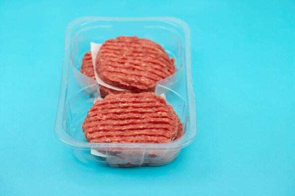 fresh raw minced meat in plastic box on blue paper