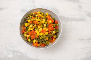 Mavi kağıdın üzerindeki kasede taze sebzeler var.