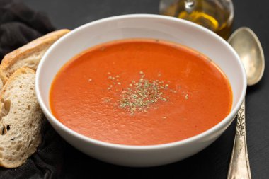 fresh cold tomato soup with herbs in the bowl on ceramic