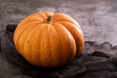 Gri seramik peçeteli taze turuncu balkabağı. Üst görünüm.