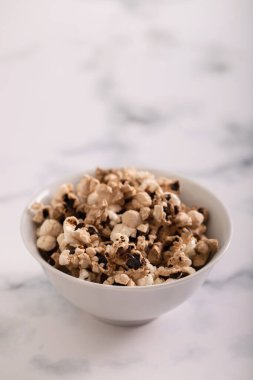 Gri seramik üzerinde küçük beyaz kasede yanmış patlamış mısır.