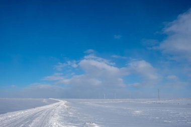 Kışın güneşli bir günde yol karla kaplıydı.