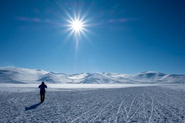 Karla kaplı yol ve güneşli kış gününde insan.