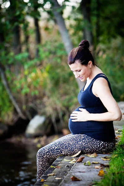 Gravid kvinna utövar yoga på stranden Stockbild