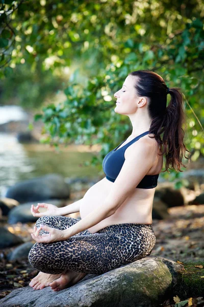 Gravid kvinna utövar yoga på stranden Royaltyfria Stockbilder