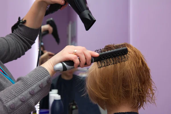 Hairdresser drying woman hair in salon — Stock Photo, Image