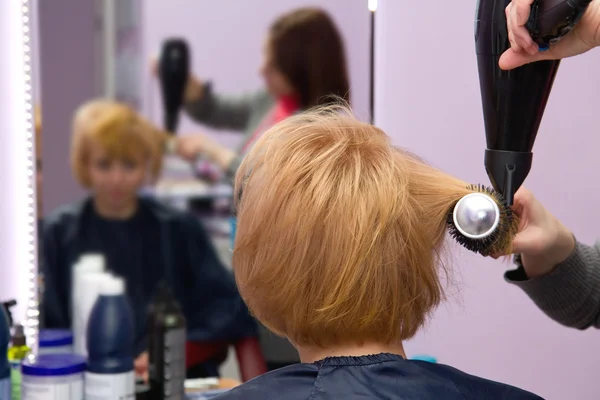 Hairdresser drying woman hair in salon — Stock Photo, Image