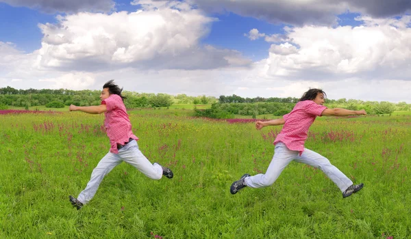 Young men running on grass — Stock Photo, Image