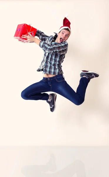 Happy man in santa cap jumping with gifts — Stock Photo, Image