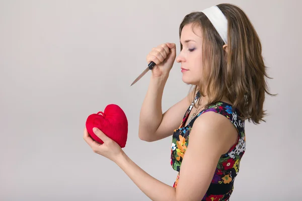 Woman cutting a heart toy with a knife — Stock Photo, Image