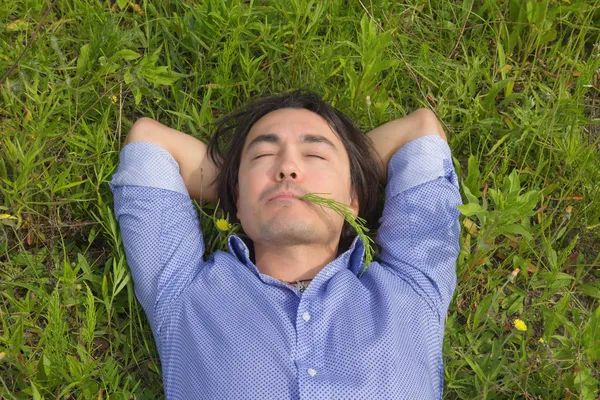 Jeune homme couché sur l'herbe verte — Photo
