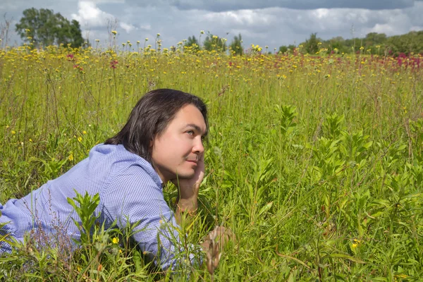 Jonge man liggen op een voorjaar weide — Stockfoto