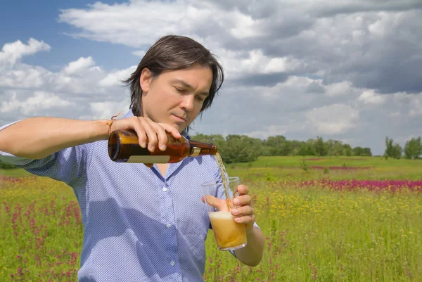 Man pouring himself a beer on a spring meadow — Stock Photo, Image