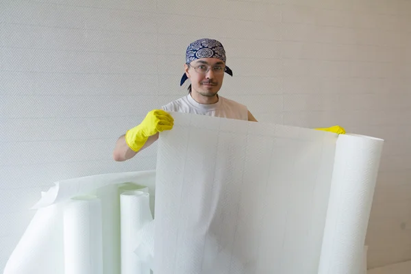 Young worker holding roll of wallpaper — Stock Photo, Image