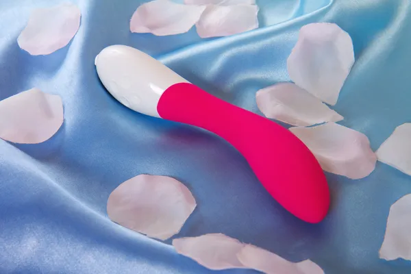 Sex toy vibrator on blue with petals — Stock Photo, Image