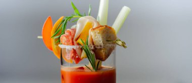 Kokteyl bardağının üstünde küçük bir aperatifle ilginç dekorasyonlu Bloody Mary, tazelik içeceği.