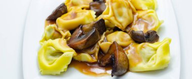 Taze yumurtalı makarna, ricotta peyniri ve porcini mantarı dolgu, lezzetli tortelloni, geleneksel İtalyan yemeği.