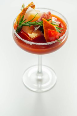 Kokteyl bardağının üstünde küçük bir aperatifle ilginç dekorasyonlu Bloody Mary, tazelik içeceği.
