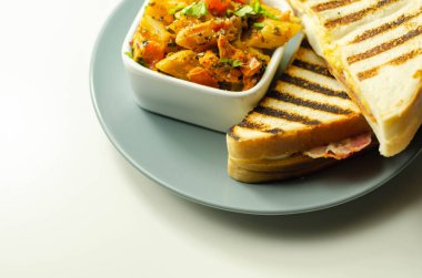 Kayın ağacından yapılmış pastırma, yumurta, mayonez ve domatesli beyaz ekmek. Parmesan peynirli Sezar makarnası, sabah yemeği.