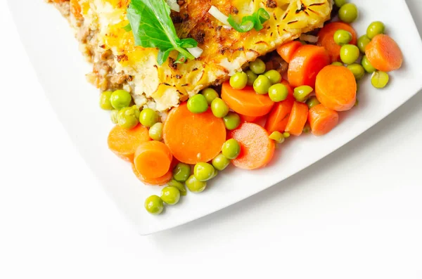 Shepherd\'s pie, tender minced lamb with garden veg in a hearty gravy beneath butter mash with carrots and green peas, traditional british meal