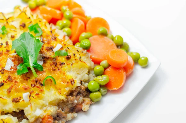 Shepherd\'s pie, tender minced lamb with garden veg in a hearty gravy beneath butter mash with carrots and green peas, traditional british meal