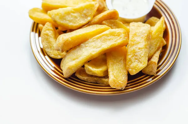 Deep fried and crispy delicious fries on the ceramic plate with garlic dip, fast food