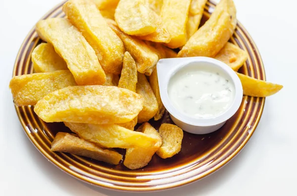 Deep fried and crispy delicious fries on the ceramic plate with garlic dip, fast food