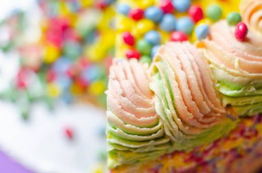 Sarı krema kaplı Madeira süngeri, erik ve ahududu reçeli katmanlı, çok renkli çikolata parçacıkları ile doldurulmuş ve üzeri çok renkli dondurmalar ve şeker süslemeleri ile süslenmiş, pinata keki.