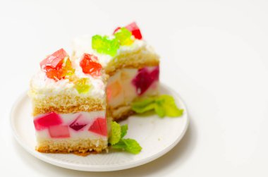 Renkli jöle parçalarıyla bir porsiyon kremalı pasta ve üzerine hindistancevizi gevreği serpiştirilmiş, parti pastası.