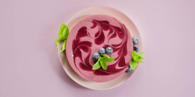 Fırınlanmış vanilya ve çilek aromalı cheesecake, sindirim bisküvisi kırıntısında yabanmersini sosu, şekerleme.