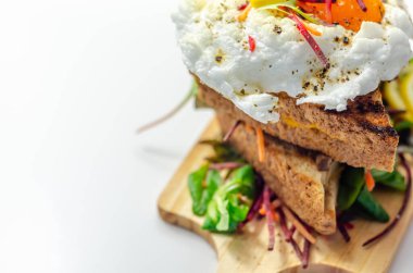 Izgara sandviçlerin üstünde yumurta, sosis, domates ve mayonez, hepsi taze salata ve lezzetli bir kahvaltıyla servis ediliyor.