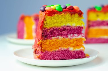 Gökkuşağı kutlama pastası, kremayla kaplanmış renkli sünger pastası ve gevrek bir şeker kabuğunda meyveli turta ile süslenmiş meyveli şekerle süslenmiş el pastası.