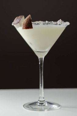 Hindistan cevizi parçaları ve hindistan cevizi parçalarıyla süslenmiş roma dayalı martini bardağında hindistan cevizi kokteyli.