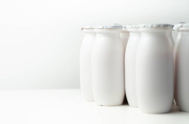 Beyaz arka planda beyaz plastik yoğurt şişeleri, süt ürünleri için tipik ambalaj, ürün şişesi