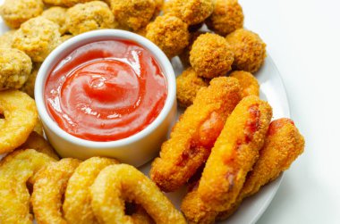 Güney usulü kızarmış tavuk, soğan halkaları ve mozzarella çubuğu beyaz tabakta domates sosu ve parti yemeği ile servis edilir.