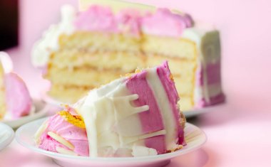 Nemli madeira süngeri, erik ve ahududu reçeli katmanlı, beyaz ve pembe donlarla kaplı, beyaz çikolata süslemeleri ile süslenmiş, doğum günü pastası