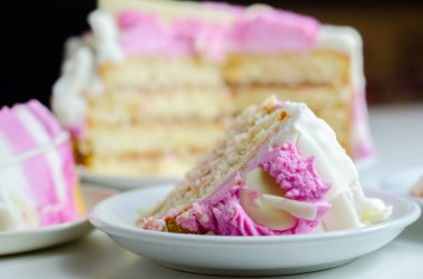 Nemli madeira süngeri, erik ve ahududu reçeli katmanlı, beyaz ve pembe donlarla kaplı, beyaz çikolata süslemeleri ile süslenmiş, doğum günü pastası