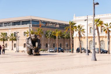 CARTAGENA, SPAIN - 22 FEBRUARY 2019 Statue bronze represents the figure of a seated man, naked and helpless, hugging his legs and with his head down, in an almost fetal position