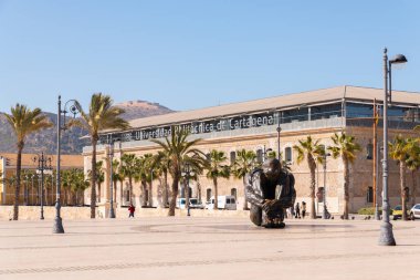 CARTAGENA, SPAIN - 22 FEBRUARY 2019 Statue bronze represents the figure of a seated man, naked and helpless, hugging his legs and with his head down, in an almost fetal position