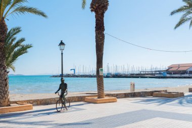 LOS ALCAZARES, SPAIN - 25 Şubat 2019 Los Alcazares şehri 50 yılı aşkın süredir popüler bir aktör tarafından seçilen bir tatil beldesiydi, ölümünden sonra kendisine ithaf edilen bir heykel, onu tipik bir resimde, bisiklette ve şapkada tasvir eder.