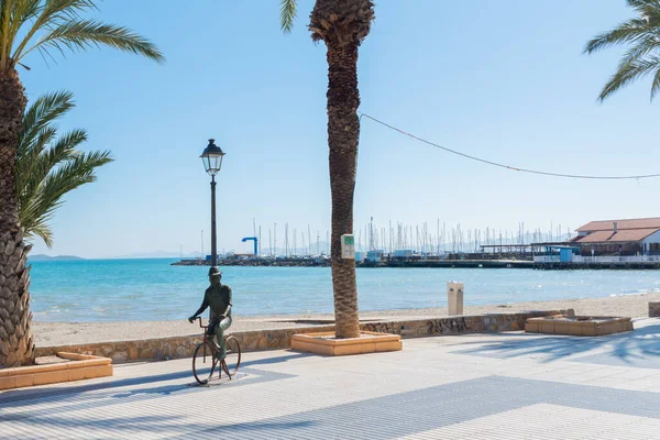 LOS ALCAZARES, SPAIN - 25 Şubat 2019 Los Alcazares şehri 50 yılı aşkın süredir popüler bir aktör tarafından seçilen bir tatil beldesiydi, ölümünden sonra kendisine ithaf edilen bir heykel, onu tipik bir resimde, bisiklette ve şapkada tasvir eder.