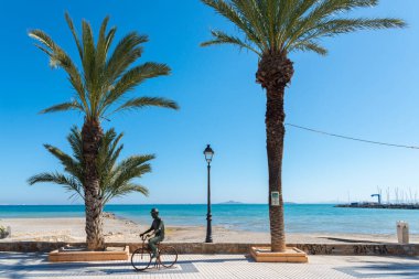 LOS ALCAZARES, SPAIN - 25 Şubat 2019 Los Alcazares şehri 50 yılı aşkın süredir popüler bir aktör tarafından seçilen bir tatil beldesiydi, ölümünden sonra kendisine ithaf edilen bir heykel, onu tipik bir resimde, bisiklette ve şapkada tasvir eder.