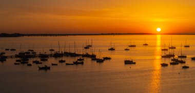 Gemiler, tekneler ve yatlar körfezde demirlemiş güneşin doğuşuna karşı, cennet gibi bir görüntü
