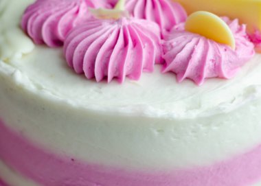 Nemli madeira süngeri, erik ve ahududu reçeli katmanlı, beyaz ve pembe donlarla kaplı, beyaz çikolata süslemeleri ile süslenmiş, doğum günü pastası