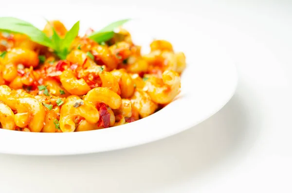 Cooked cellentani pasta with cooked chicken breast and peppers in a spicy tomato and jalapeno dressing