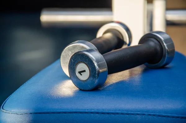 Dambıl, mavi arka planda salonda dambıl. Fitness için spor salonu. Spor salonunda egzersiz aletleri..