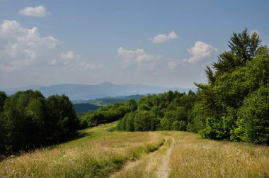 Hiking trail in the mountains highlands. Beautiful views of the mountains in the summer. Green trees and beautiful cloudy sky.
