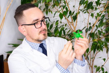 Atanan doktor ya da bilim adamı mikrobiyolog mikroorganizma modeli gösteriyor - virüs prionu ya da bakteri. Hastaya patojenin gösterimi - hastalığın nedeni ya da nedensel faktörü, rahatsızlığı