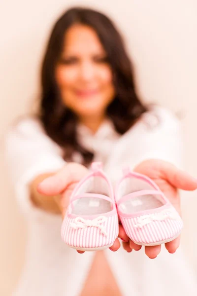 Mujer embarazada con zapatillas de bebé — Foto de Stock